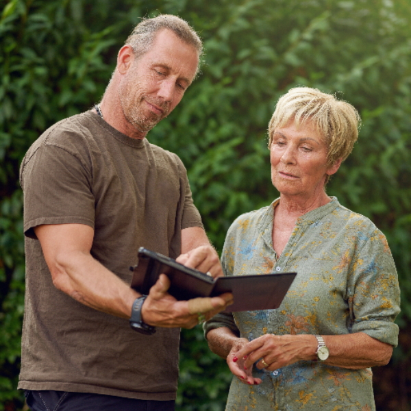 Mann und Frau inspizieren die Fassade und das Schrägdach eines Einfamilienhauses