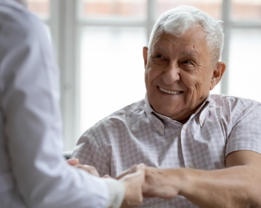 Älterer Herr schüttelt die Hand eines Treppenlift-Beraters