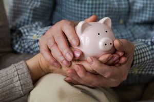 Mann und Frau die gemeinsam ein Sparschwein in der Hand halten