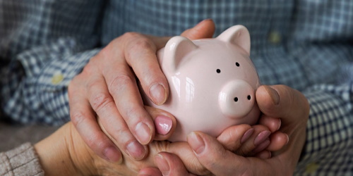 Älteres Paar hält ein Sparschwein in den Händen.