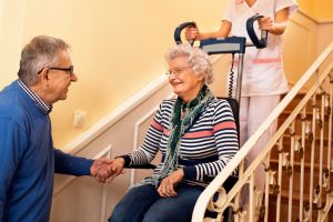 Pflegekraft transportiert Seniorin mit Treppensteiger.